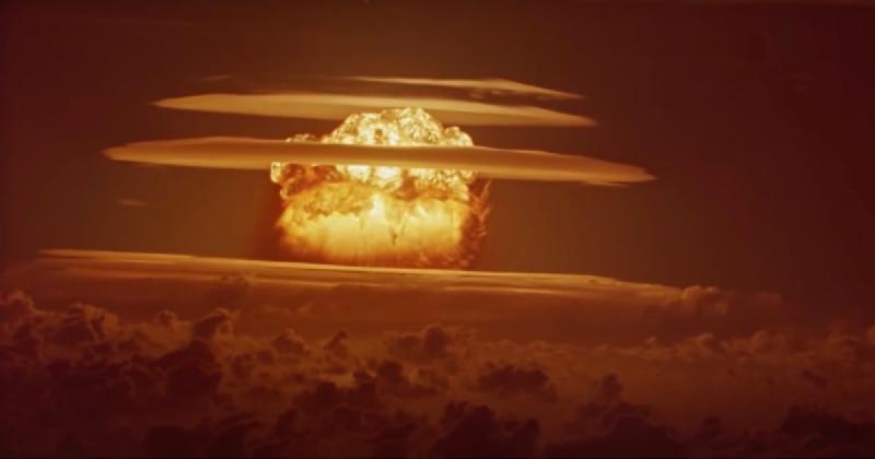 Picture of the castle bravo nuclear explosion: a massive, blindingly bright fireball at the center, glowing with intense orange and yellow light, surrounded by thick, billowing clouds of smoke and debris.